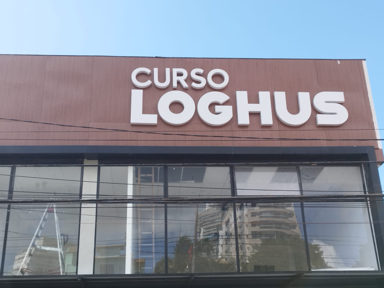 Vista frontal da fachada do Curso Loghus Macaé com letreiro iluminado